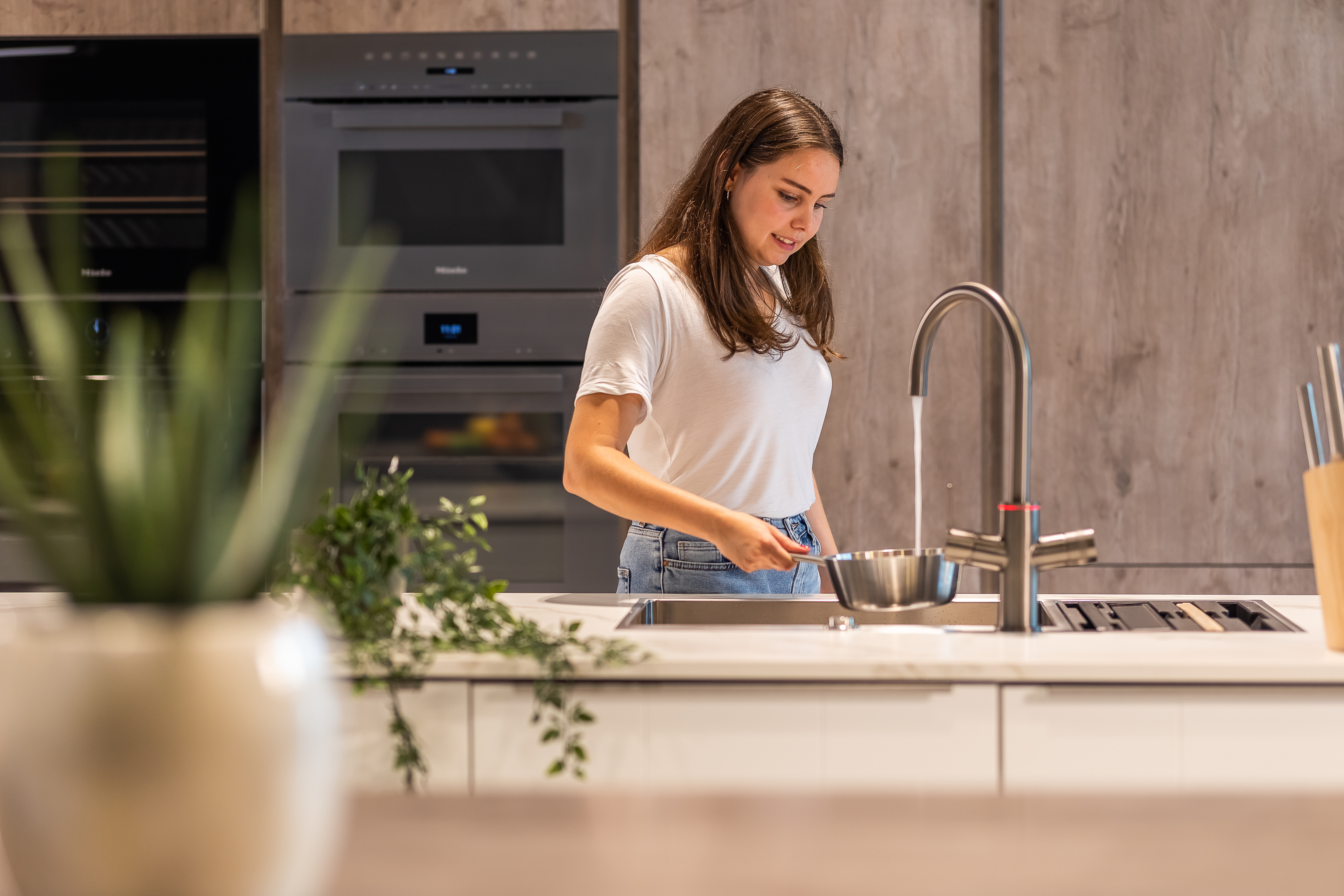 Meisje tapt kokend water uit een Unito kraan in de keuken